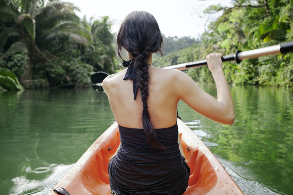 Rear View Of Woman Kayaking On Lake At Forest