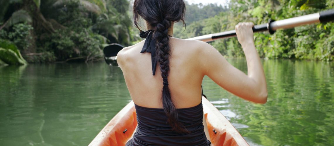 Rear View Of Woman Kayaking On Lake At Forest
